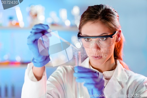 Image of Attractive young scientist pipetting.