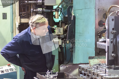 Image of Elderly worker watches on milling machine work