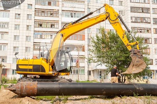 Image of Using of excavator as crane for raising of pile