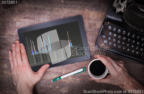 Image of Tablet touch computer gadget on wooden table, graph