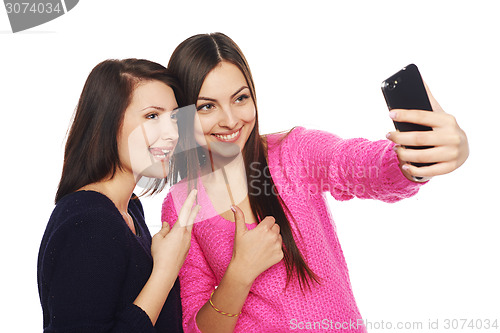 Image of Two girls friends taking selfie with smartphone