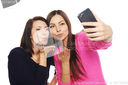 Image of Two girls friends taking selfie with smartphone