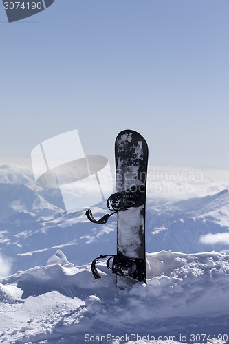 Image of Snowboard in snow on off-piste slope at sun day