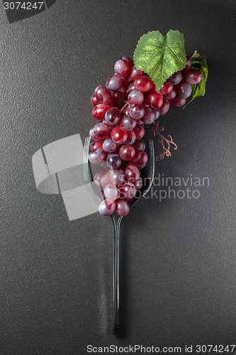 Image of Wine glass made of forks and grape on black