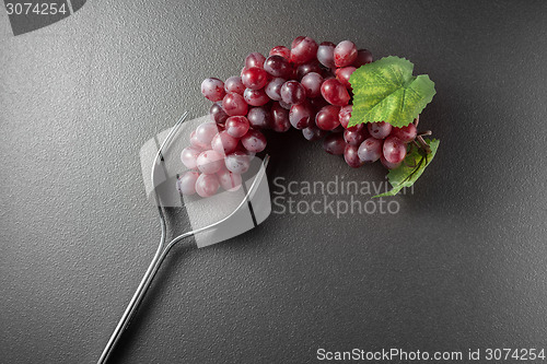 Image of Wine glass made of forks and grape on black