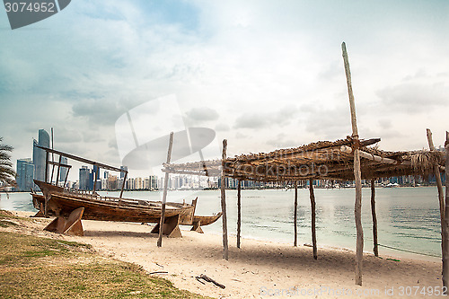 Image of sea beach with old wooden boath and luxury skyscarper