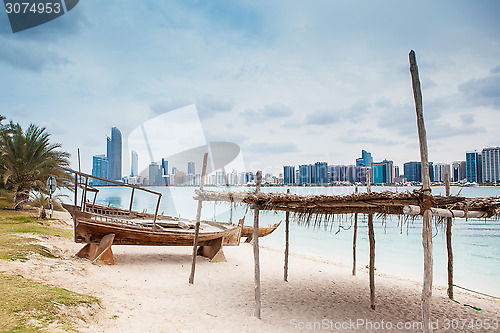 Image of sea beach with old wooden boath and luxury skyscarper