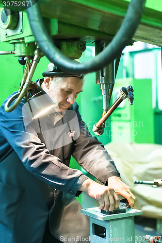 Image of Elderly worker watches on milling machine work