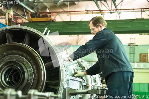 Image of Elderly mechanic assembles aviation engine