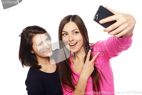 Image of Two girls friends taking selfie with smartphone