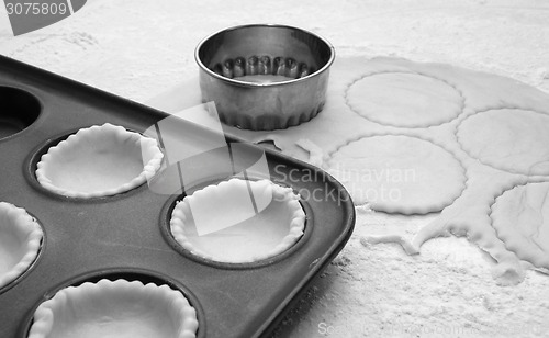 Image of Pastry circles cut and lining a metal bun tin