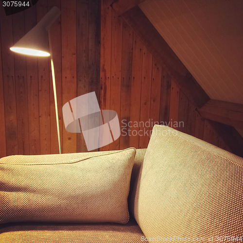 Image of Sofa and lamp in a room with wooden walls