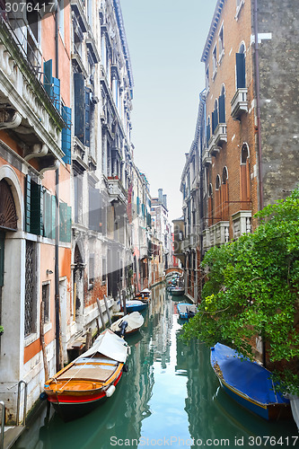 Image of Gondolas moored in water canal next to buildings