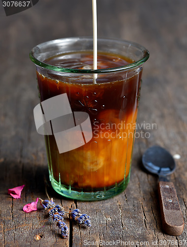 Image of Pouring milk into a glass of black coffee