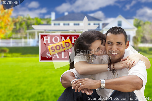 Image of Hispanic Couple, New Home and Sold Real Estate Sign