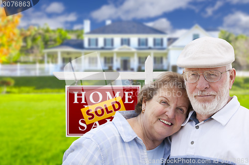 Image of Senior Couple in Front of Sold Real Estate Sign and House