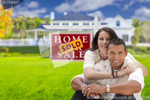 Image of Hispanic Couple, New Home and Sold Real Estate Sign