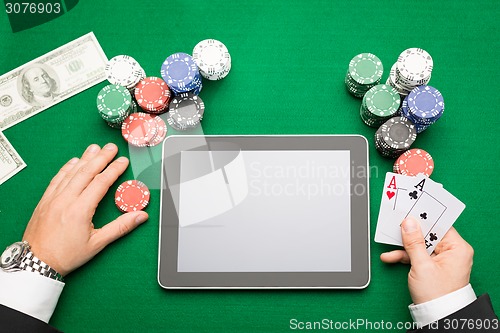 Image of casino poker player with cards, tablet and chips