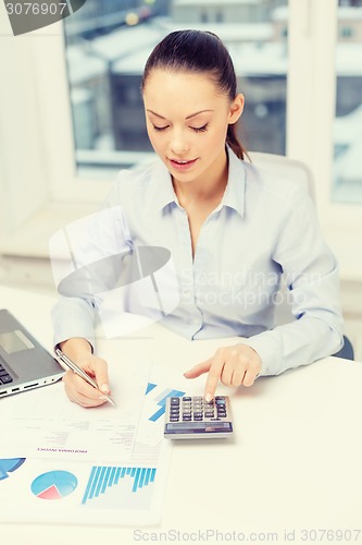 Image of businesswoman with laptop and charts in office