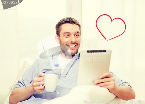 Image of smiling man working with tablet pc at home