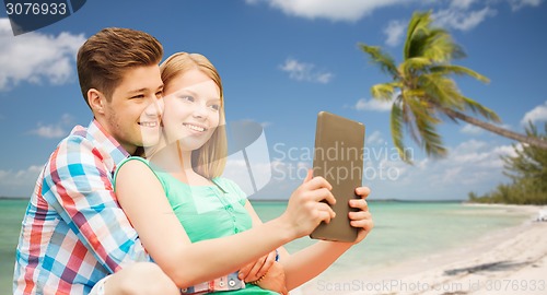 Image of couple with tablet pc taking selfie over beach