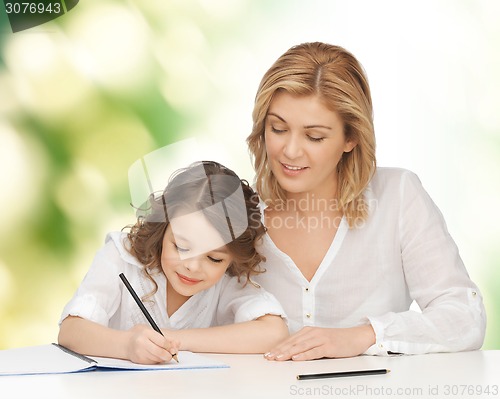 Image of happy mother and daughter writing in notebook