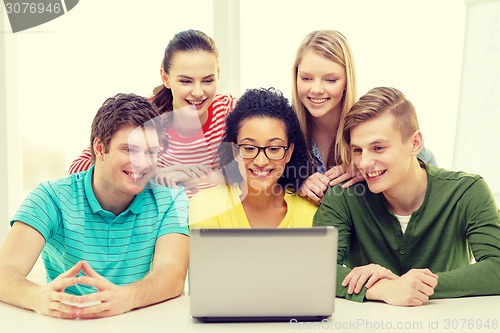 Image of smiling students looking at laptop at school