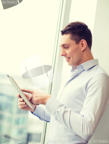 Image of smiling businessman with tablet pc in office