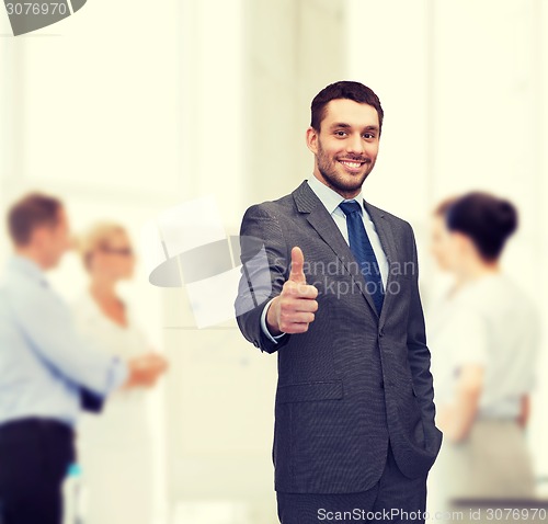 Image of handsome buisnessman showing thumbs up in office