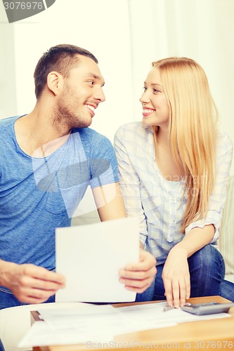 Image of smiling couple with papers and calculator at home