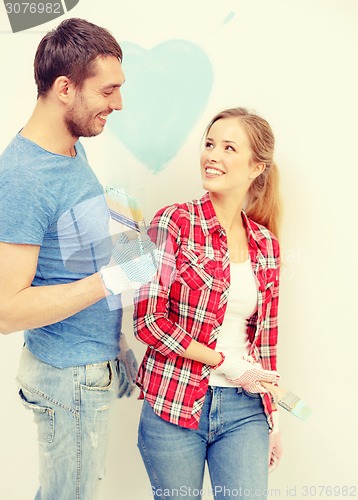 Image of smiling couple painting small heart on wall