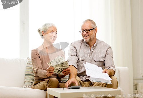 Image of senior couple with money and calculator at home