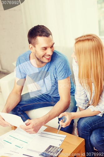 Image of smiling couple with papers and calculator at home