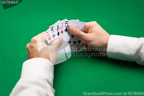 Image of poker player holding playing cards at casino table