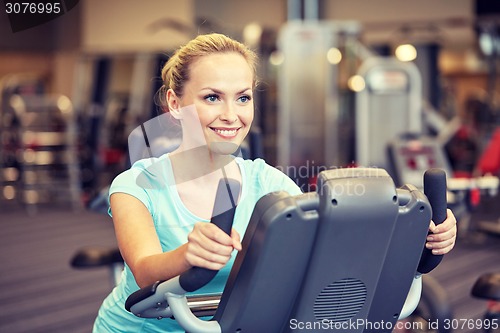 Image of smiling woman exercising on exercise bike in gym