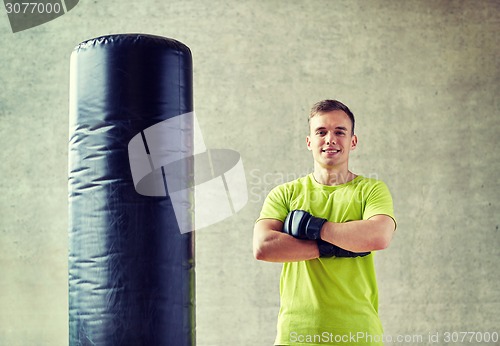 Image of man with boxing gloves and punching bag in gym