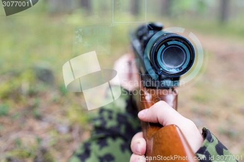 Image of close up of soldier or sniper with gun in forest