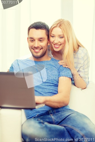 Image of smiling happy couple with laptop at home