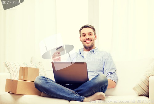 Image of man with laptop, credit card and cardboard boxes