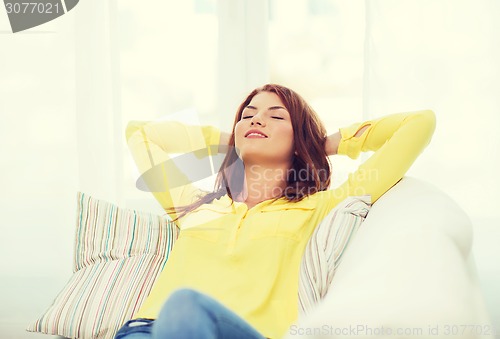 Image of smiling young woman lying on sofa at home