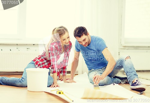 Image of smiling couple smearing wallpaper with glue