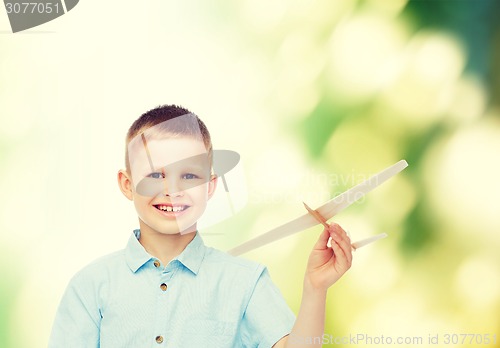 Image of smiling little boy holding a wooden airplane model