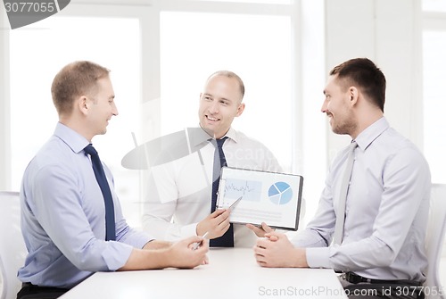 Image of smiling businessmen with papers in office