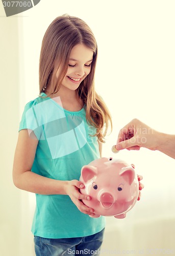 Image of smiling little girl holding piggy bank