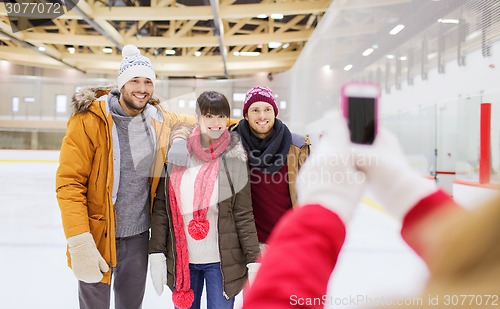 Image of happy friends taking photo on skating rink