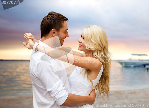 Image of happy couple hugging over sunset beach background