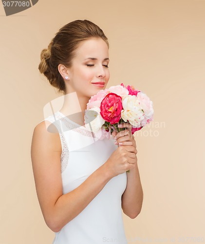 Image of smiling woman in white dress with bouquet of roses