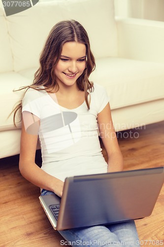 Image of smiling teenage girl with laptop computer at home