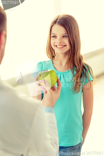 Image of male doctor giving an apple to smiling little girl