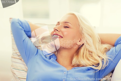 Image of smiling young woman lying on sofa at home